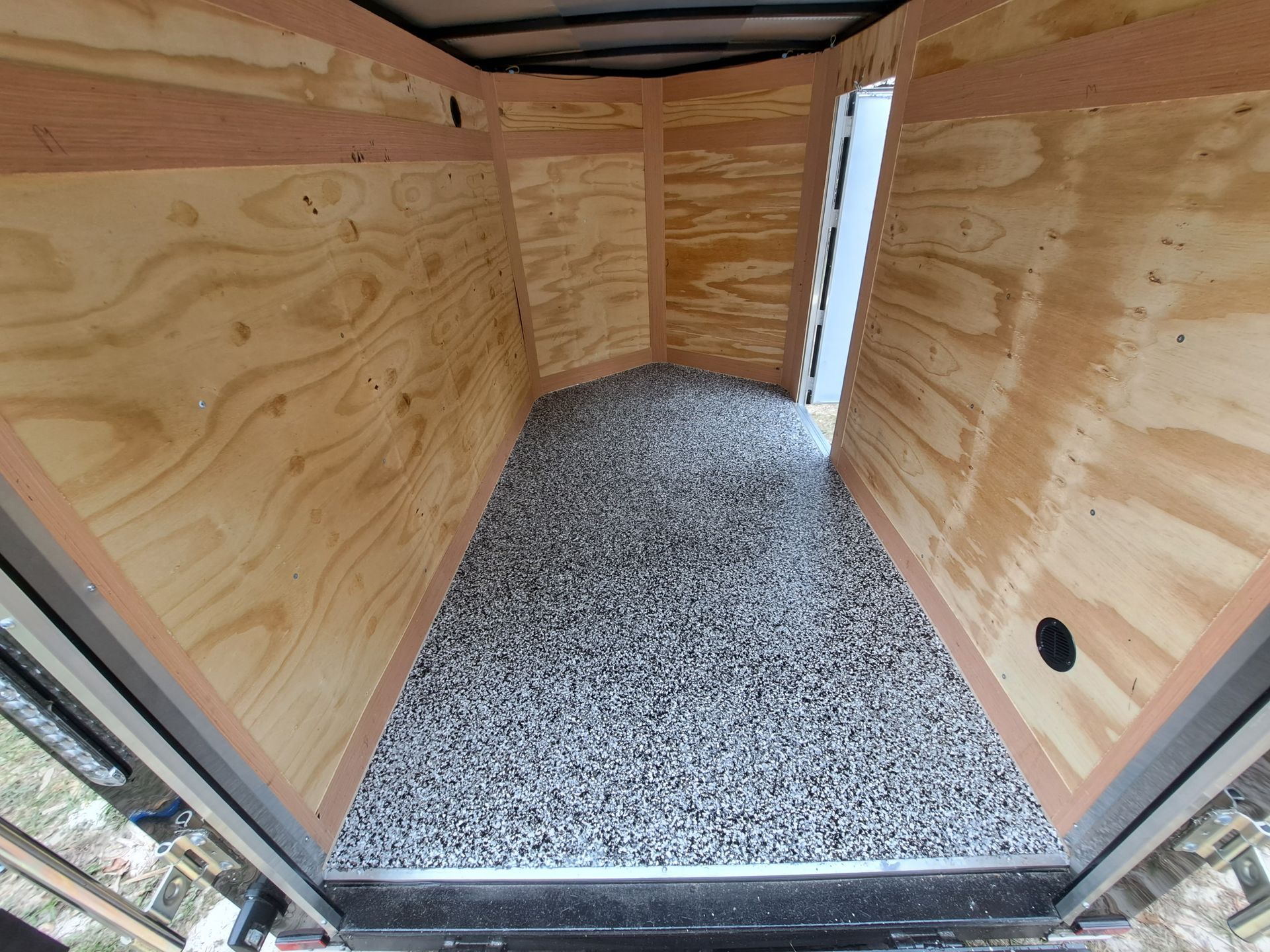 The inside of a trailer with wooden walls and a gravel floor.