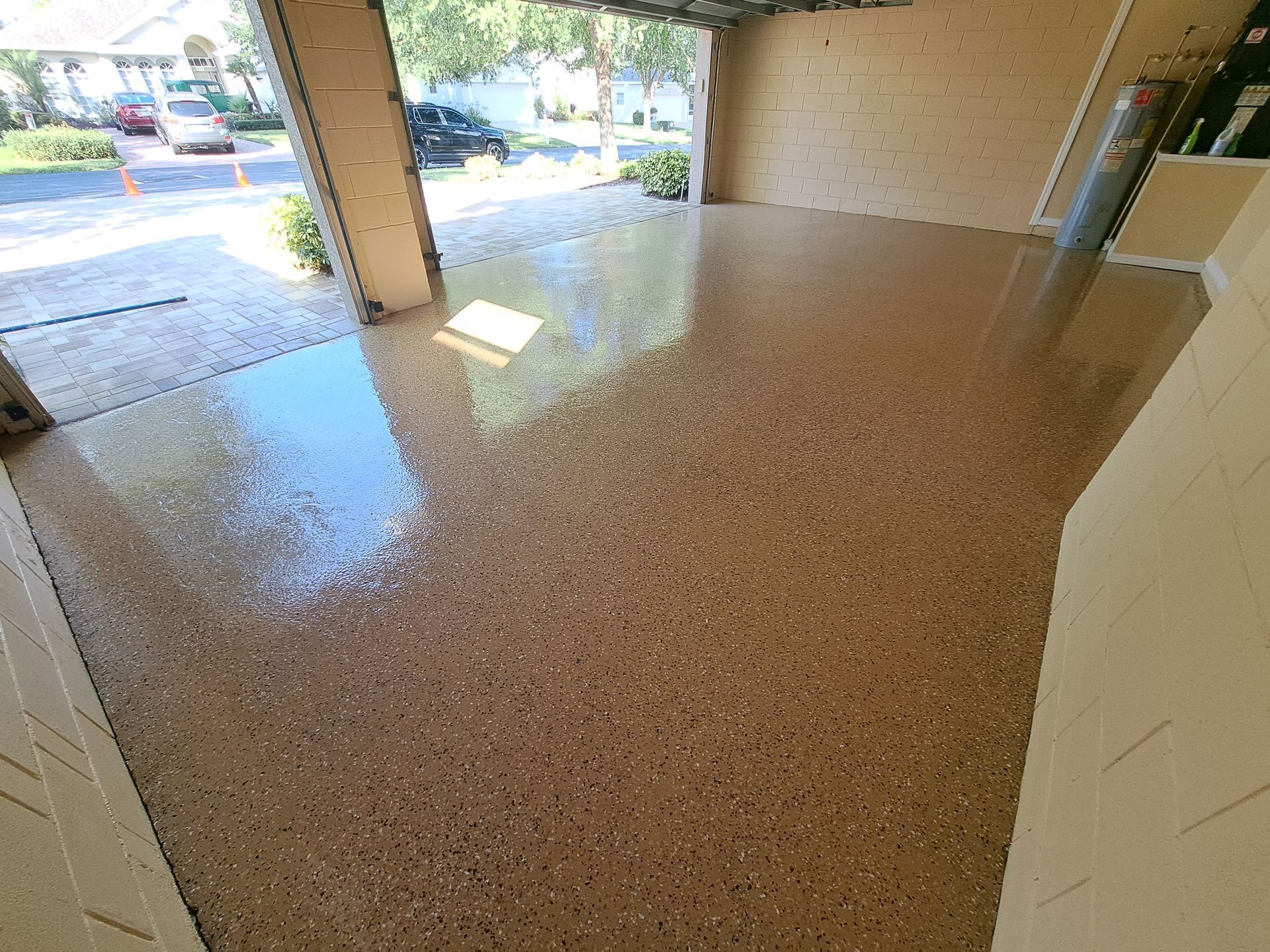 A garage with a shiny concrete floor and a garage door open.