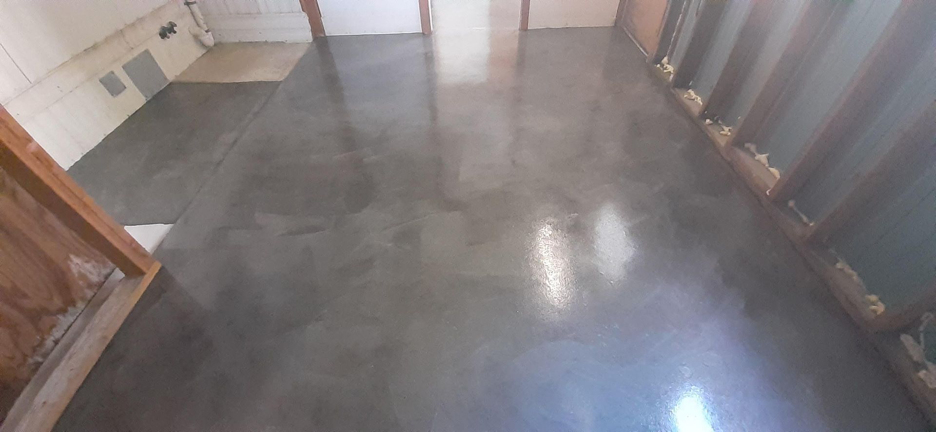 A room with a concrete floor and a wooden wall.