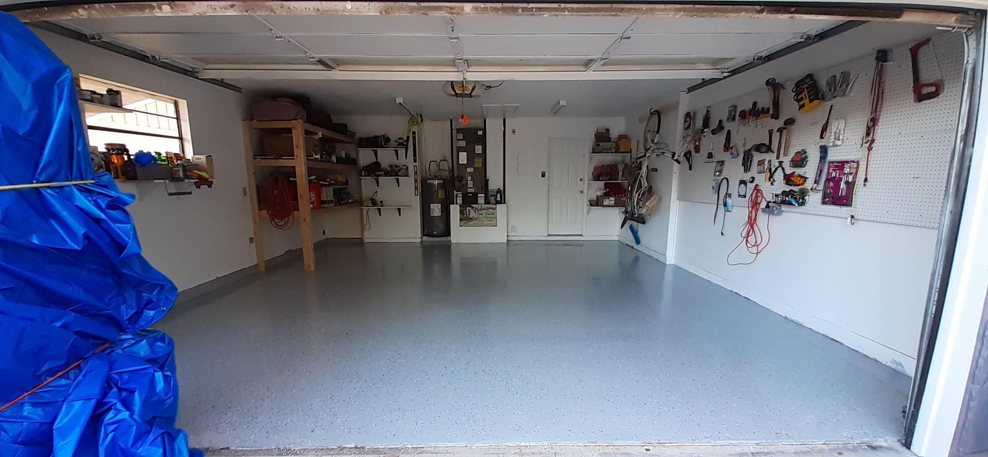An empty garage with a blue tarp covering the door