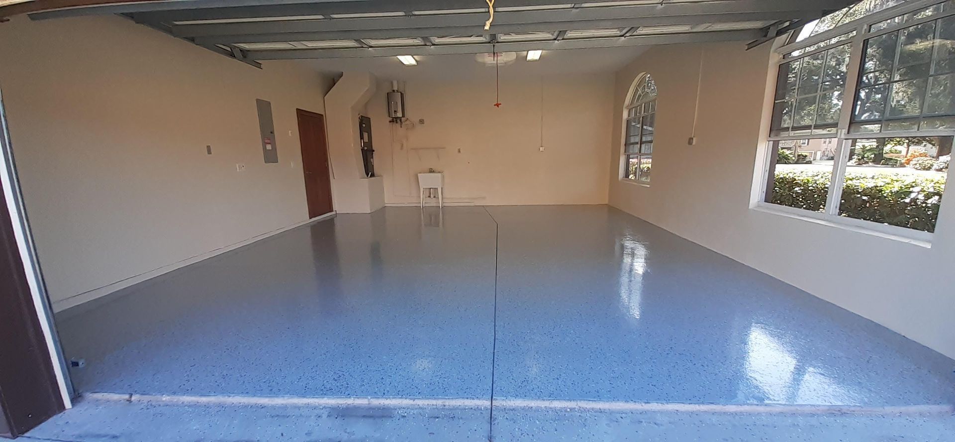 A large empty garage with a blue floor and white walls.