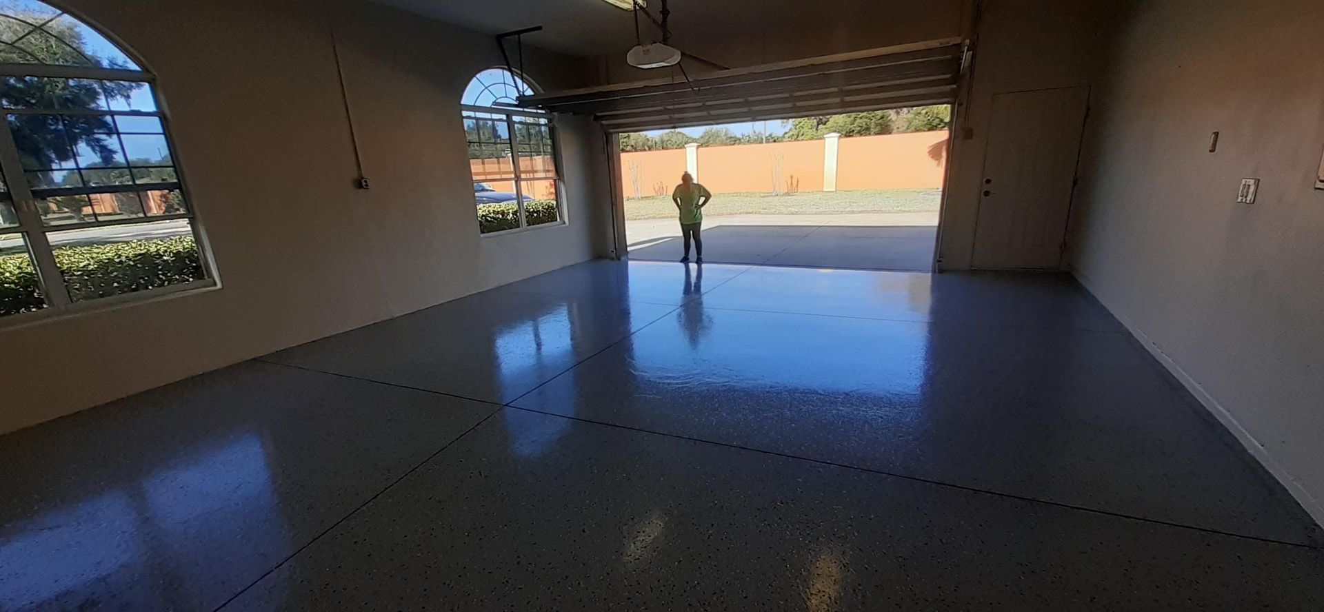A man is standing in a garage with the door open.