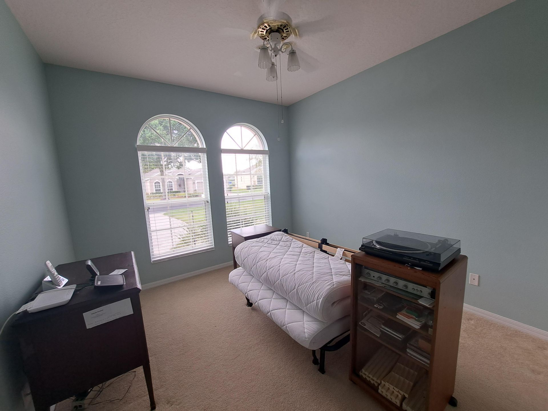 A bedroom with a couch and a ceiling fan.