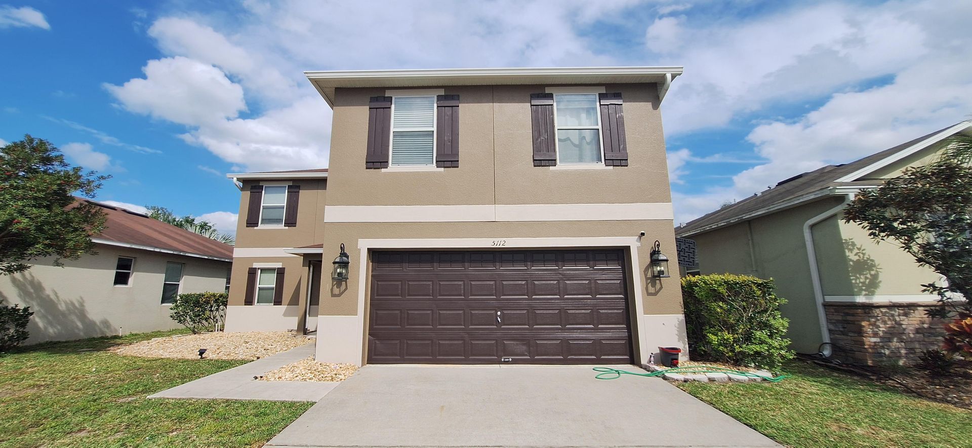The front of a house with a brown garage door and a concrete driveway.