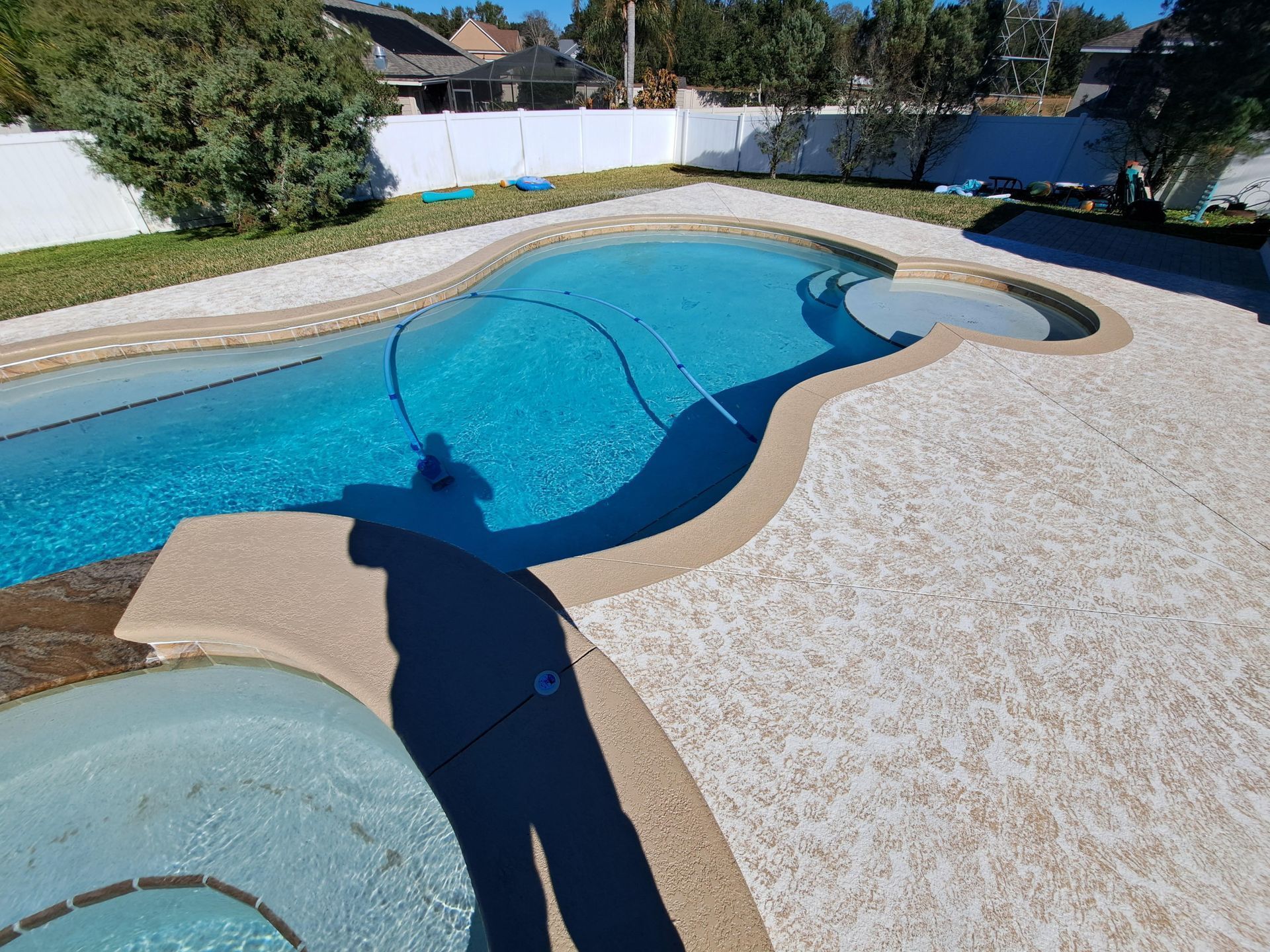A large swimming pool in a backyard with a white fence
