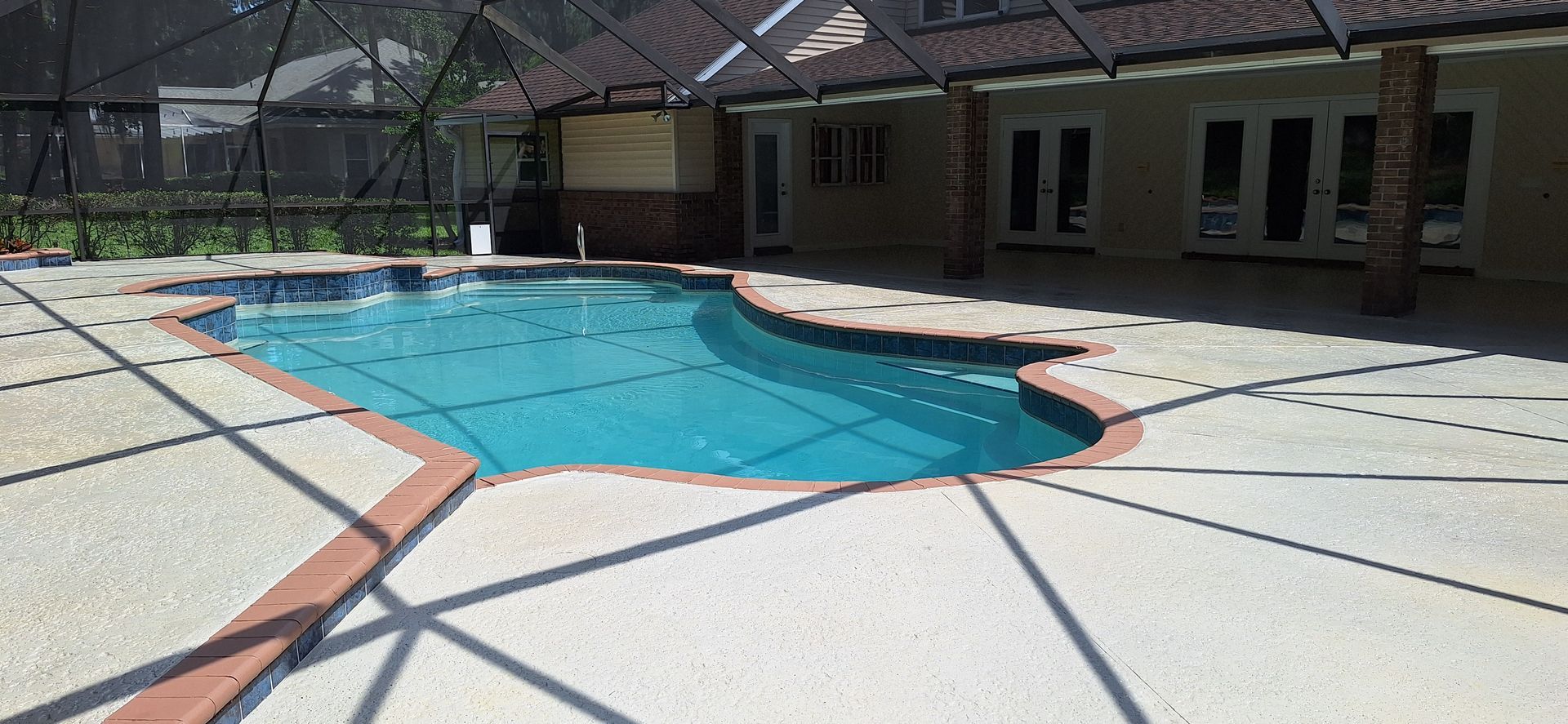 A large swimming pool is in the backyard of a house.