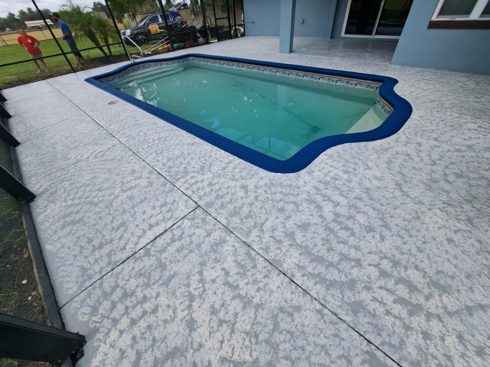 A large swimming pool is sitting on top of a concrete patio.