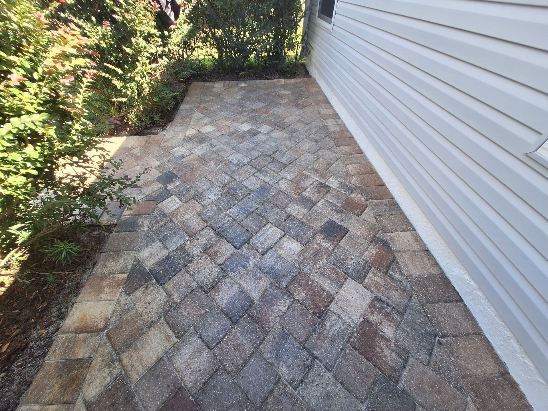 A brick walkway leading to the side of a house.