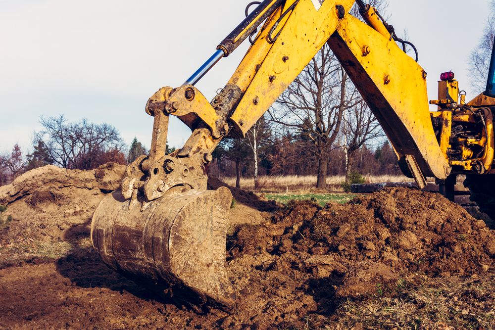 A Yellow Excavator is Digging a Pile of Dirt in a Field — Ensbey Earthmoving in Glenview, QLD