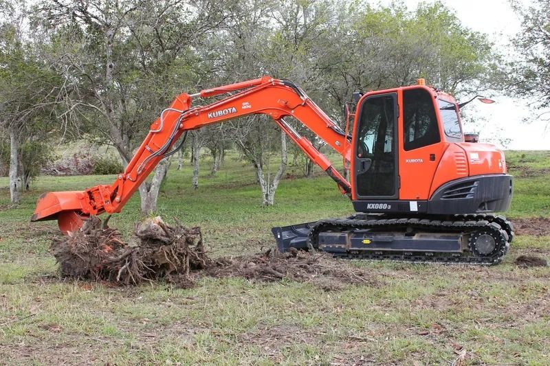 An Orange Excavator is Digging a Hole in a Grassy Field — Ensbey Earthmoving in Glenview, QLD