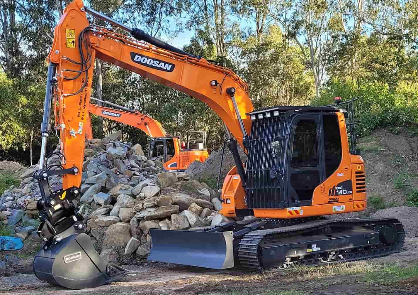 A Large Orange Excavator is Sitting on Top of a Pile of Rocks — Ensbey Earthmoving in Glenview, QLD