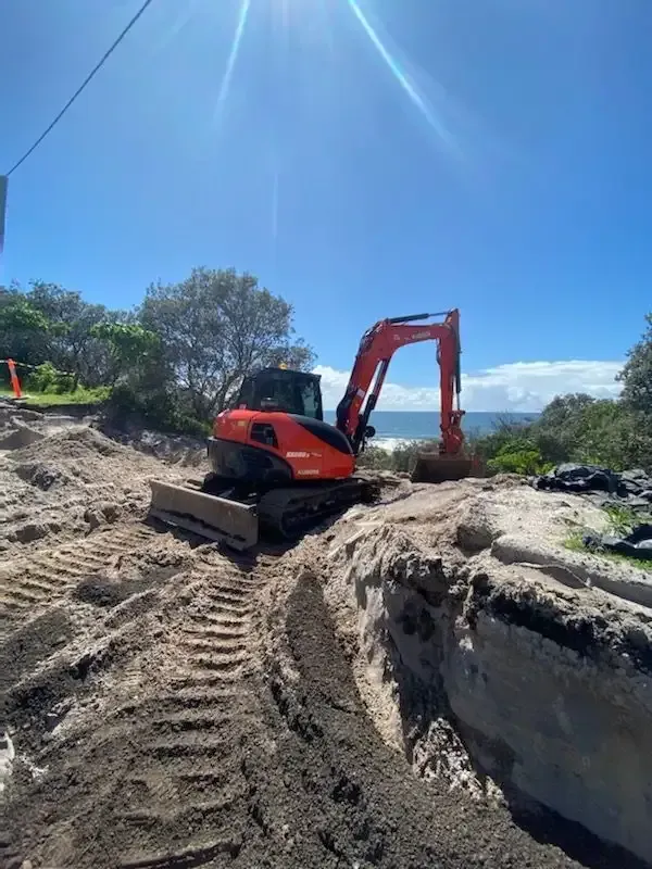 A Bulldozer is Digging a Hole in the Dirt Near the Ocean — Ensbey Earthmoving in Glenview, QLD