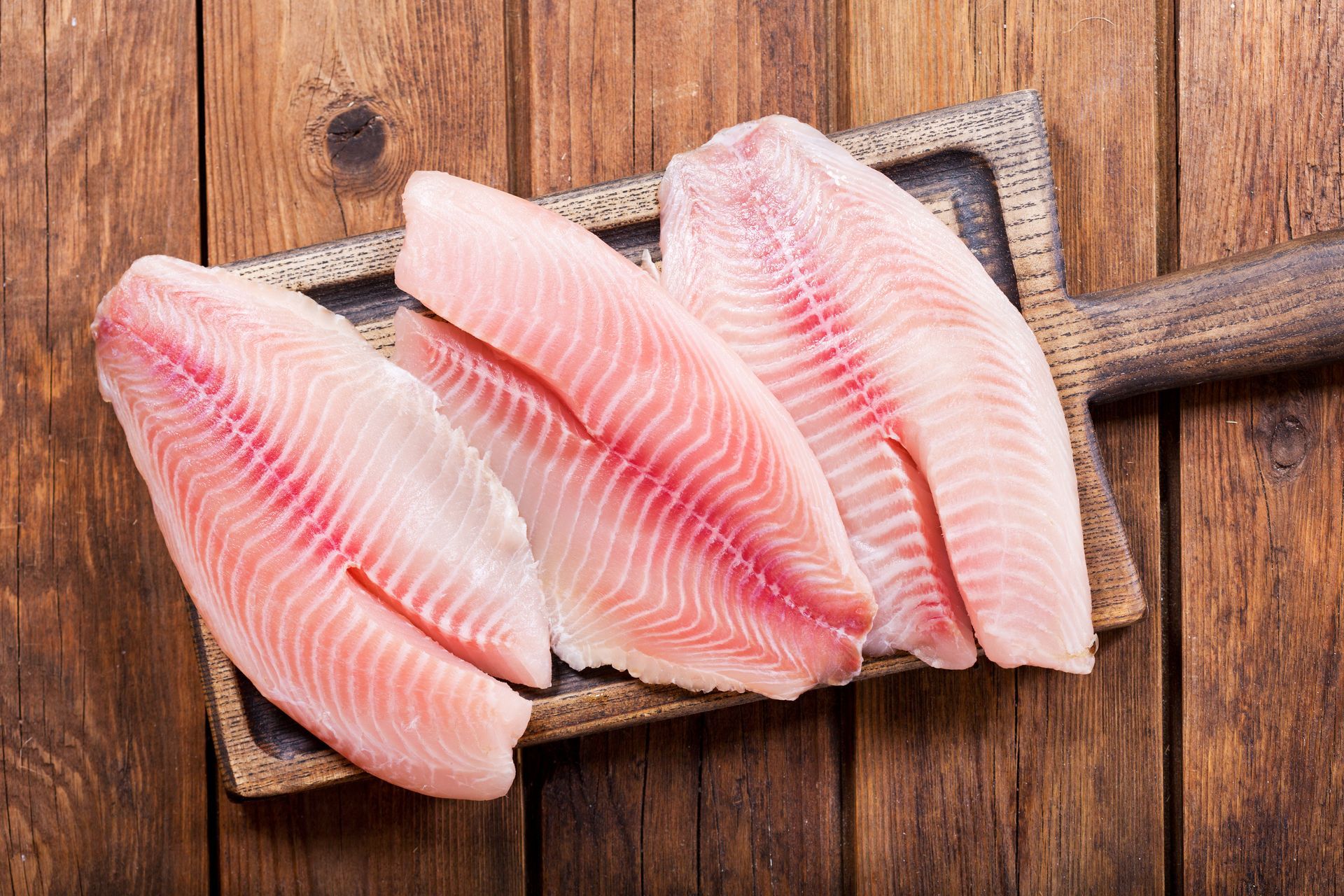 Fresh raw fish fillets on a wooden cutting board