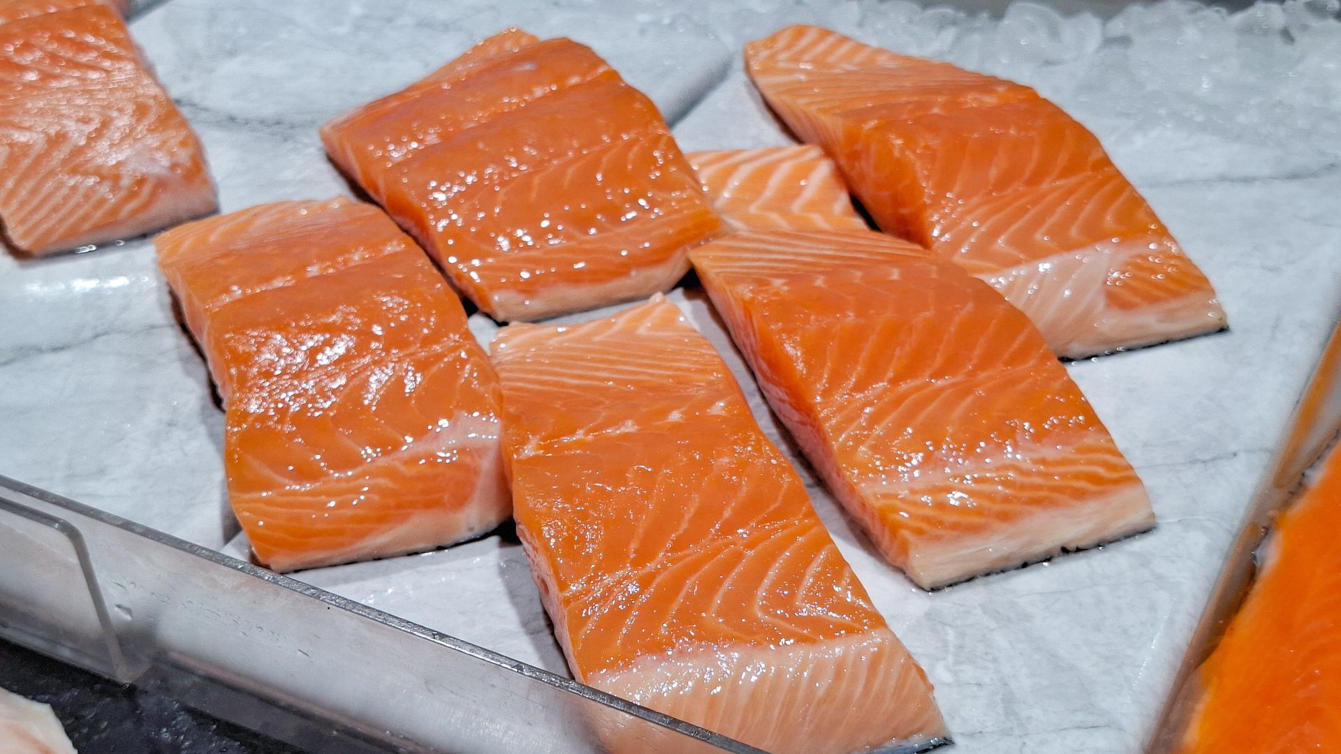 Several fresh salmon fillets laid out on a tray