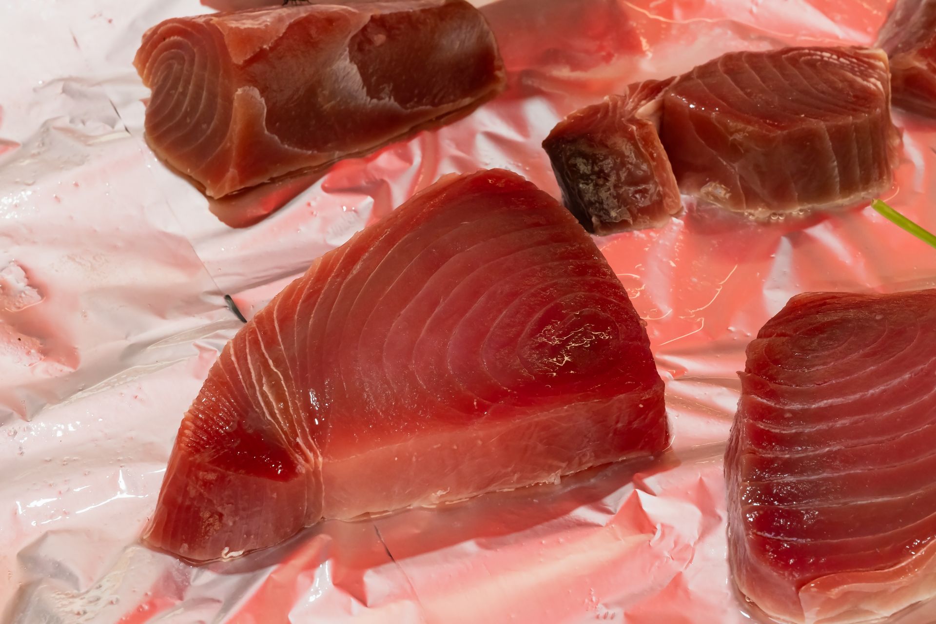 Slices of raw red fish on white paper, likely tuna steak cuts