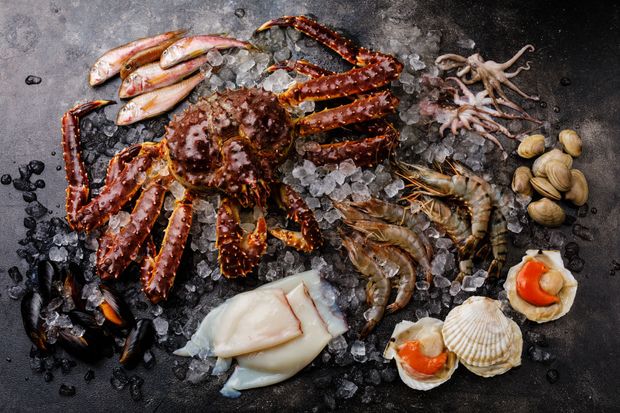 Cooked Australian Prawns, served on a black marble slate, with a fork, and sea salt rocks next to it. 