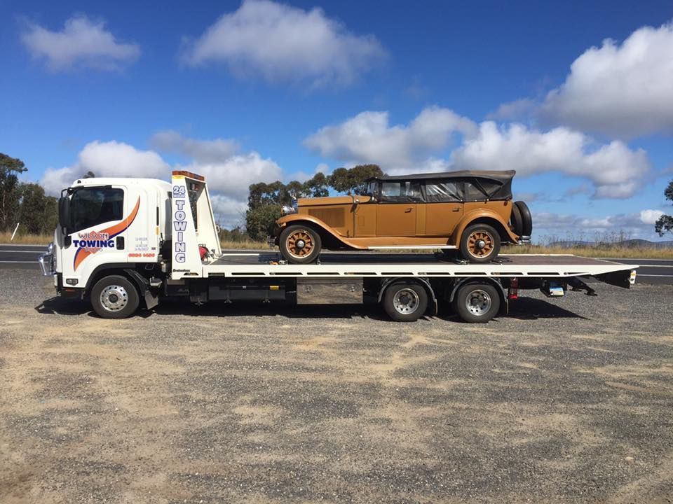 Broken red pickup car loaded onto white towing truck in public area for transportation to garage — Tow in Narromine, NSW