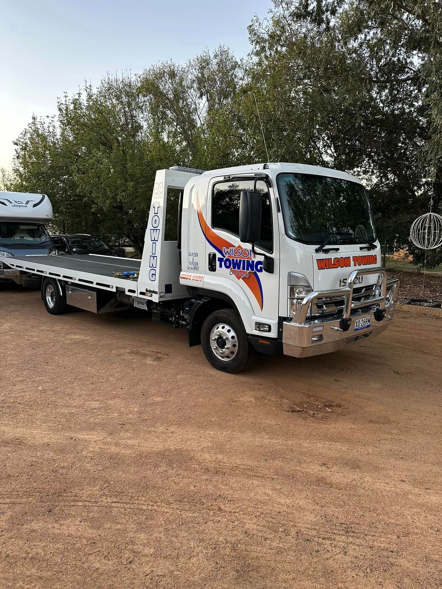 A white van chained to a modern flatbed tow truck