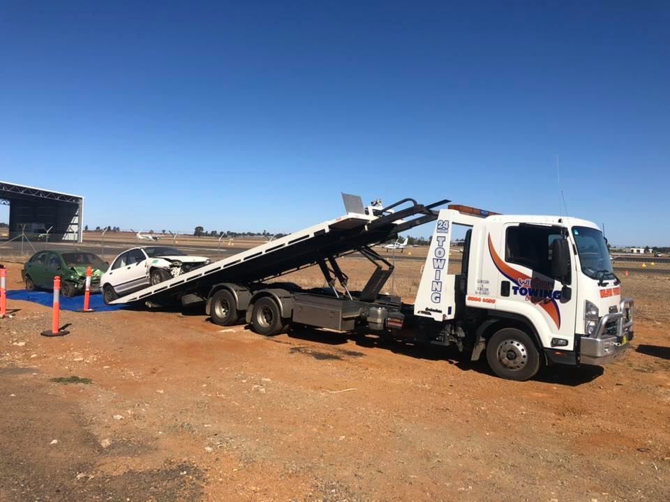 A tilt tray tow truck loading a vehicle onto the tray