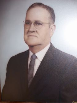 Portrait of a man in a dark suit, white shirt, and tie against a plain background.