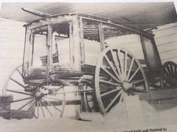 Vintage wooden wagon with large spoked wheels displayed indoors in a museum-like setting