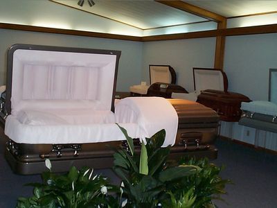 Open caskets with white linings in a selection room, with plants in the foreground
