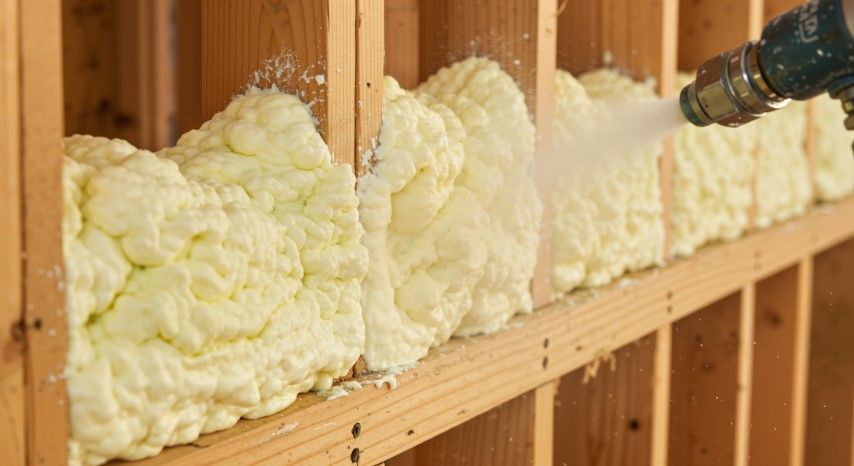 Spray foam insulation filling wall cavities inside a wooden-framed construction wall