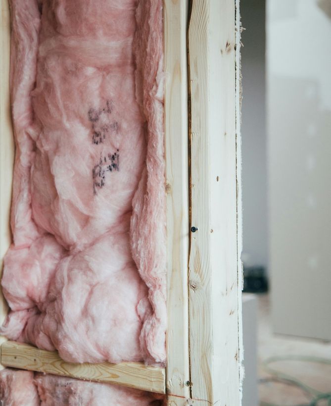 Damaged wall insulation exposed inside a doorway with pink fiberglass and framing visible
