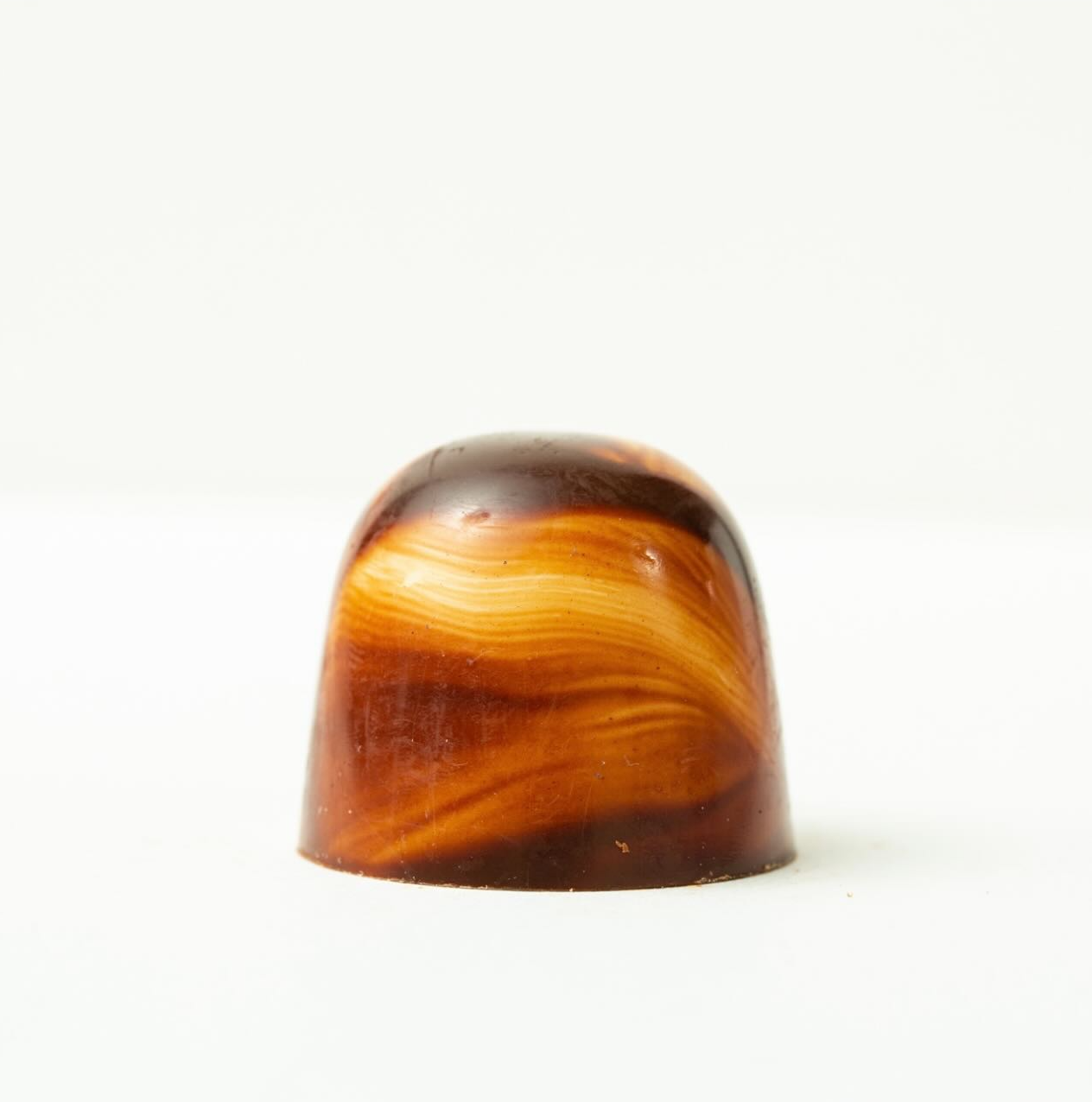 Small amber-brown translucent polished stone or candy on a white background