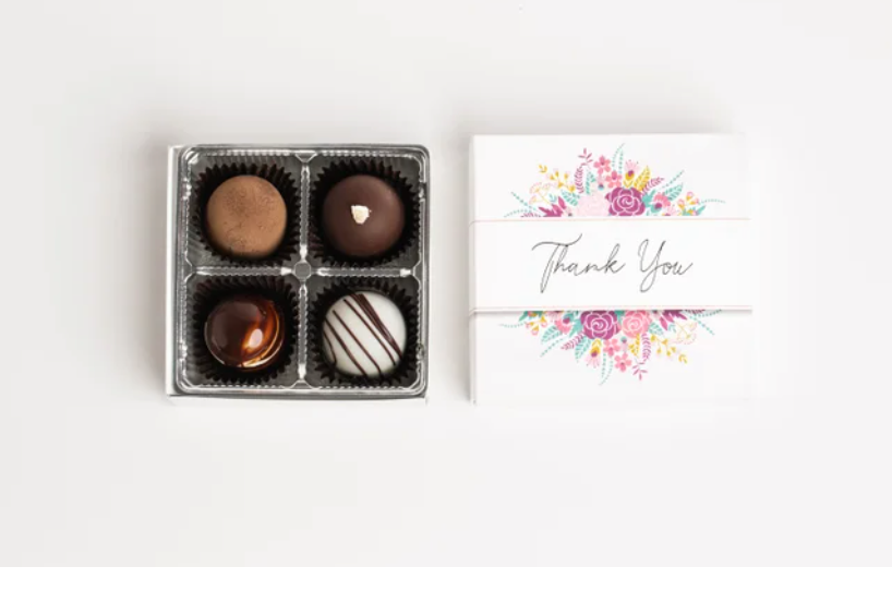 Open white candy box with assorted chocolate truffles on a white background