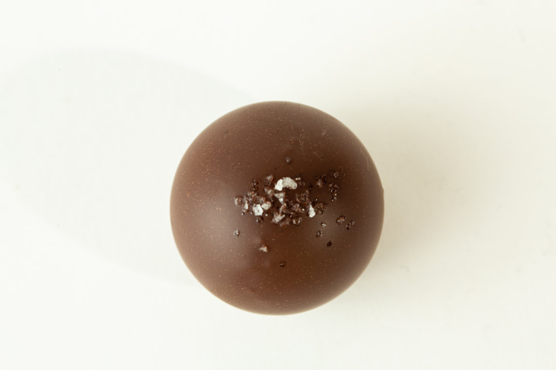 Single round chocolate dessert with a dusting of powdered sugar on a white background