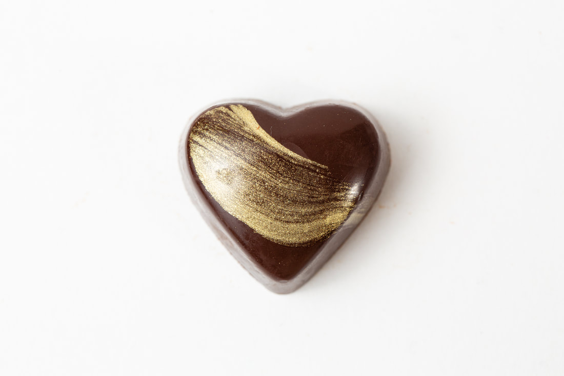 Heart-shaped chocolate with gold swirl on a white background