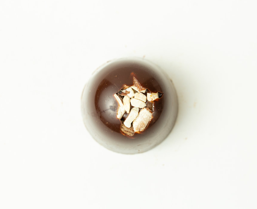 A small bowl of dark liquid with sliced garlic on top, centered on a white background