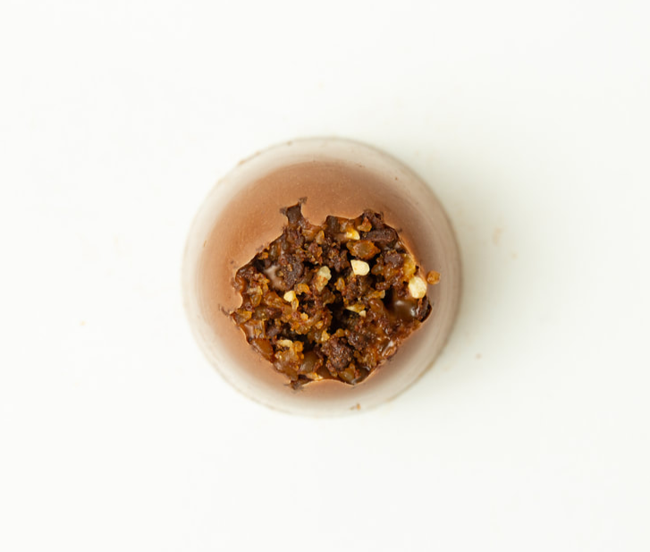 Small bowl of chunky brown seasoning or spice mix on a white background