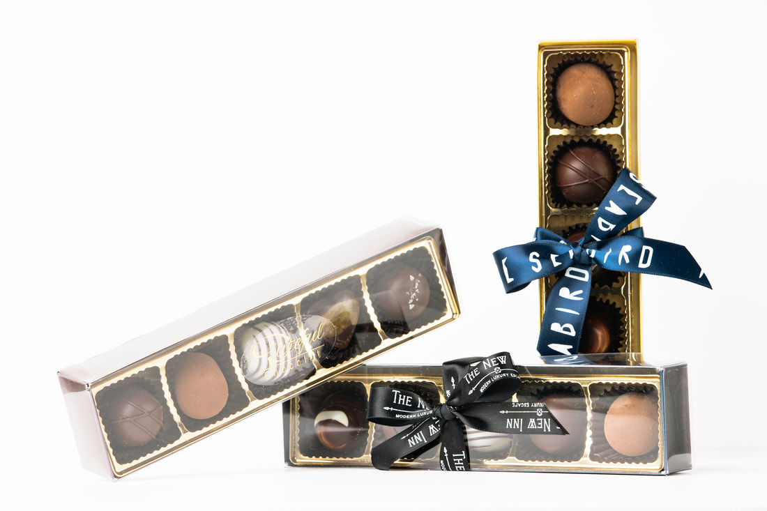 Assorted chocolate truffle gift boxes tied with black and blue ribbons on a white background