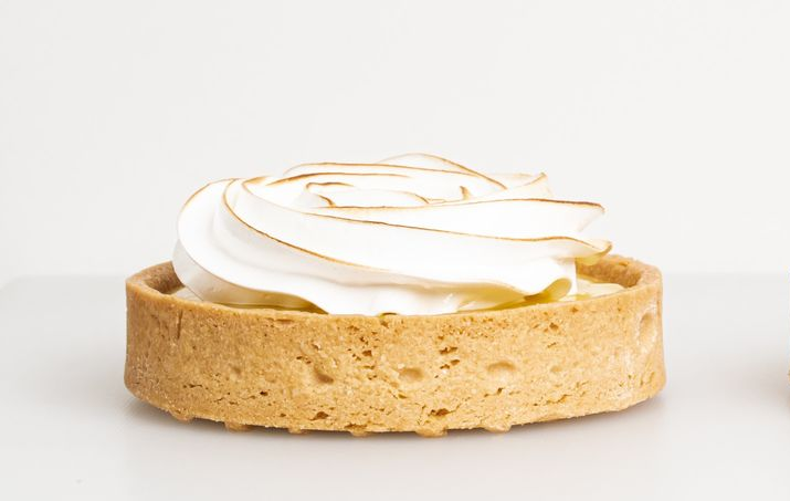 Tart shell topped with white whipped cream and caramel drizzle on a white background