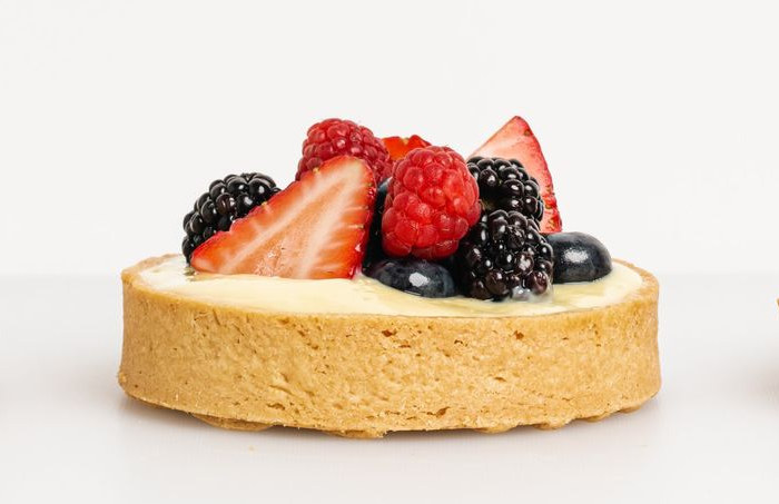 Fruit tart with strawberries, raspberries, blackberries, and blueberries on a white background