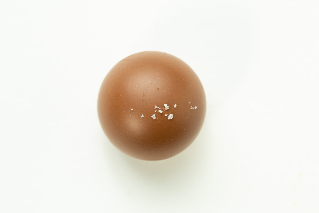 A single brown egg with small white specks on a white background