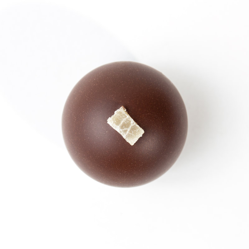 Brown chocolate truffle with a small white paper label on top, isolated on a white background