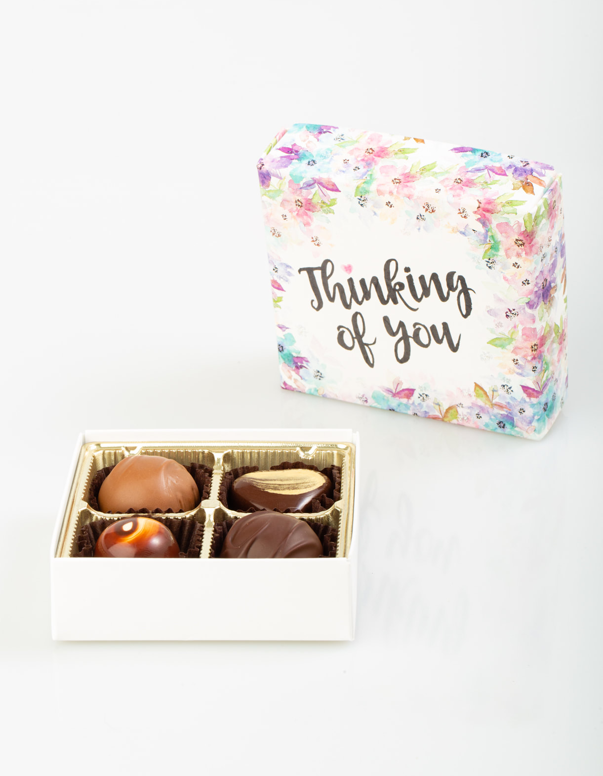 Chocolate gift box with a floral “Thinking of you” card on a white background