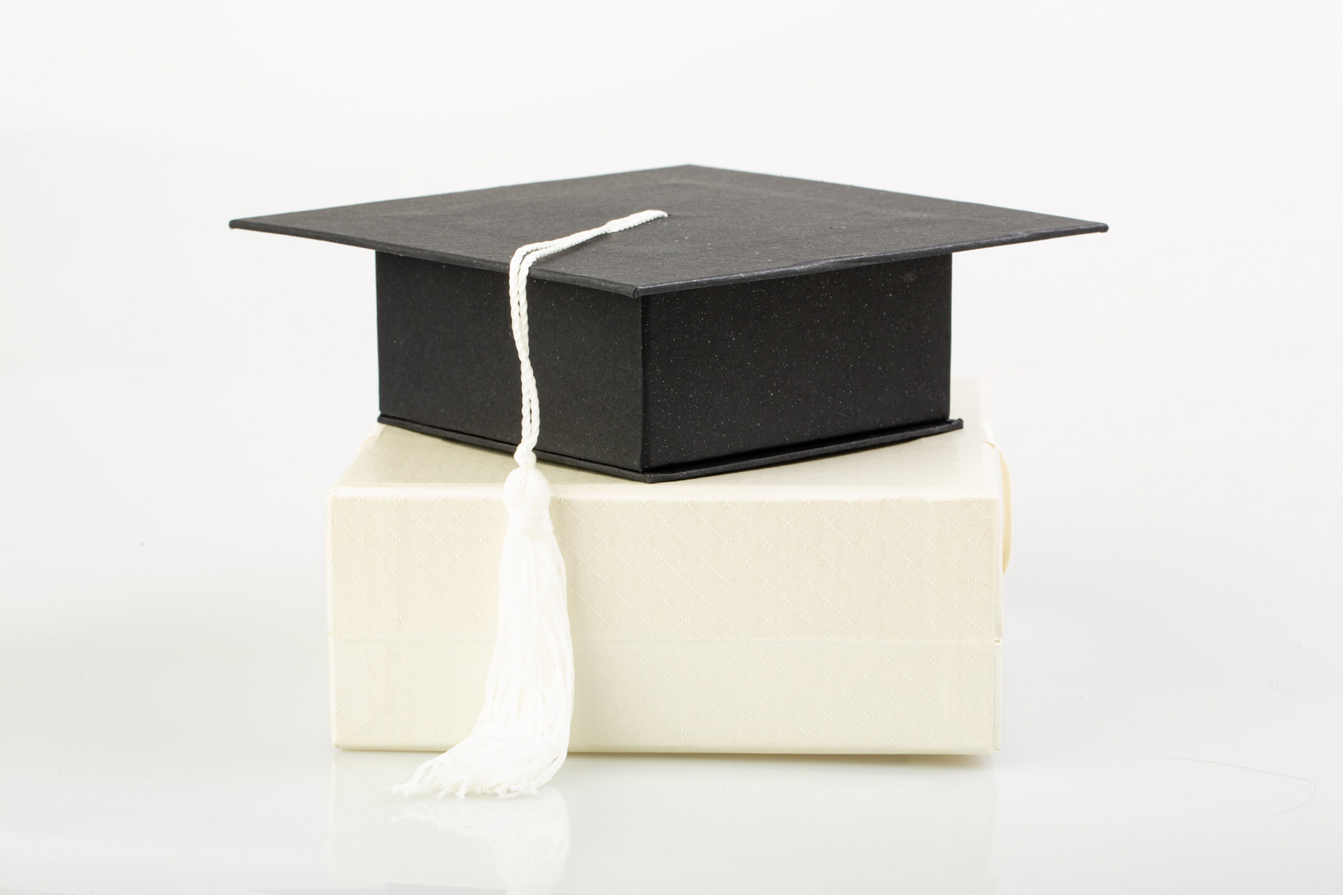 Black gift box with a white tassel lid, open to reveal assorted chocolates inside.