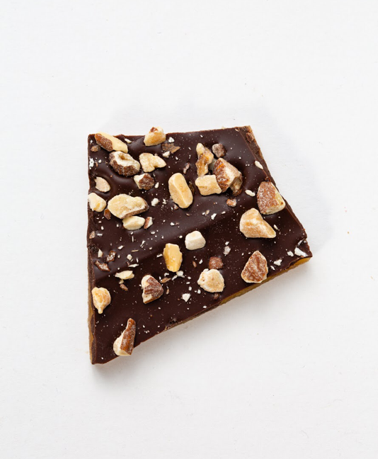 Chocolate bark topped with chopped nuts on a white background