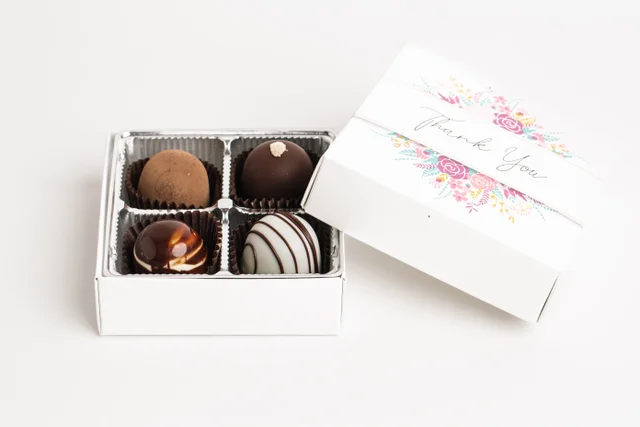 Open white candy box with assorted chocolate truffles on a white background
