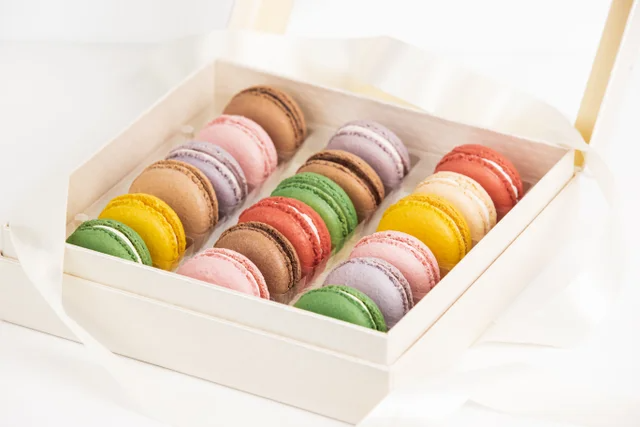 Box of assorted colorful macarons in a white pastry tray