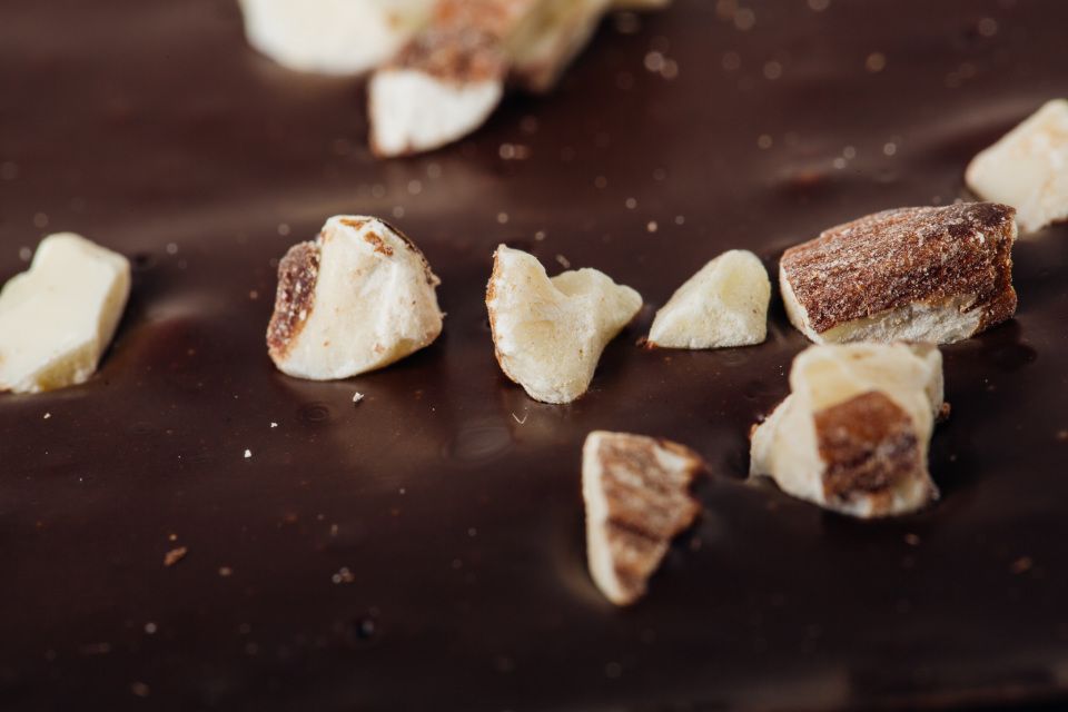 Four packaged chocolate bark varieties with nuts and fruit on a white background