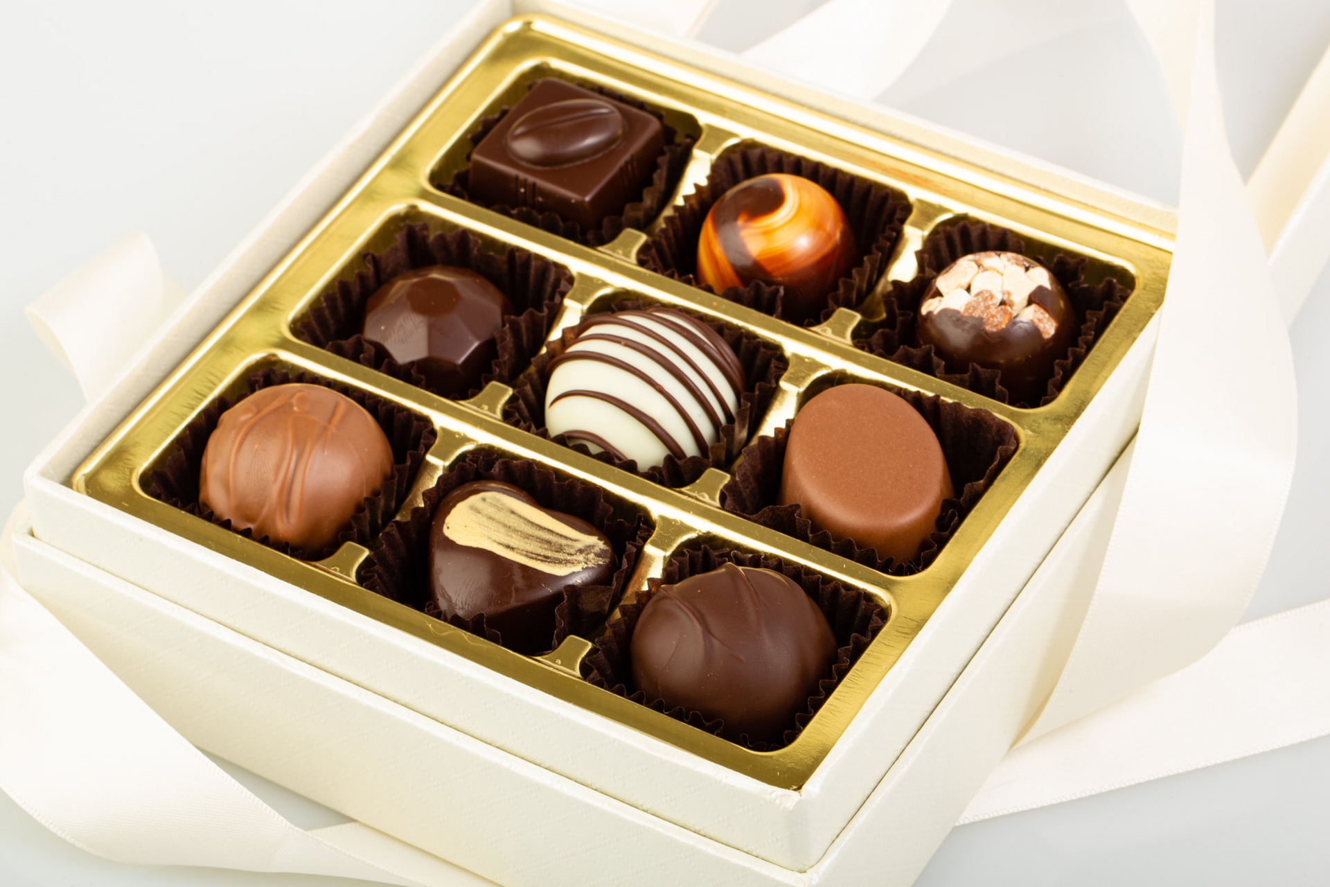 Open box of assorted chocolates in a cream-colored gift box