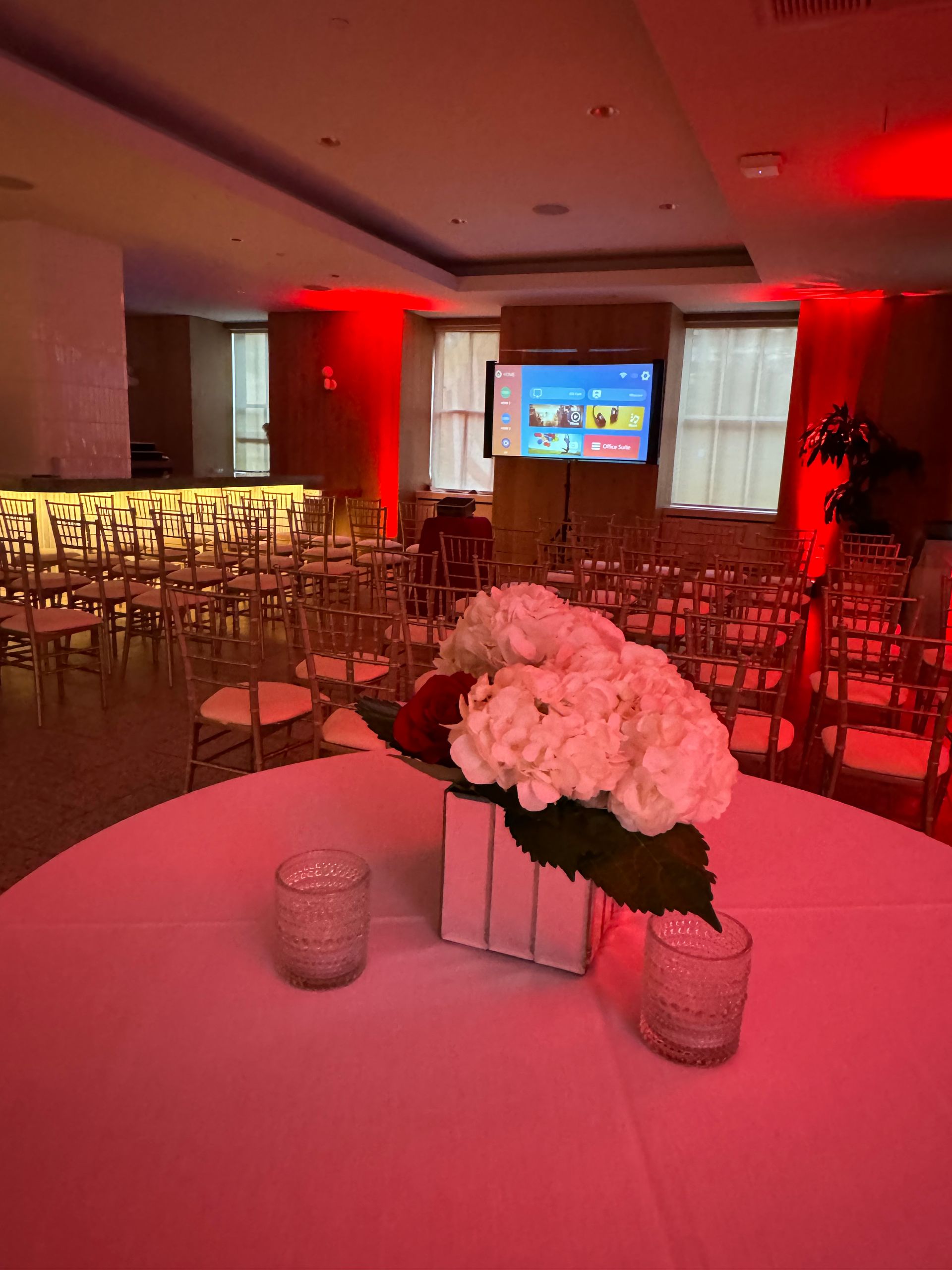 A table with flowers and candles on it in a room with red lights.