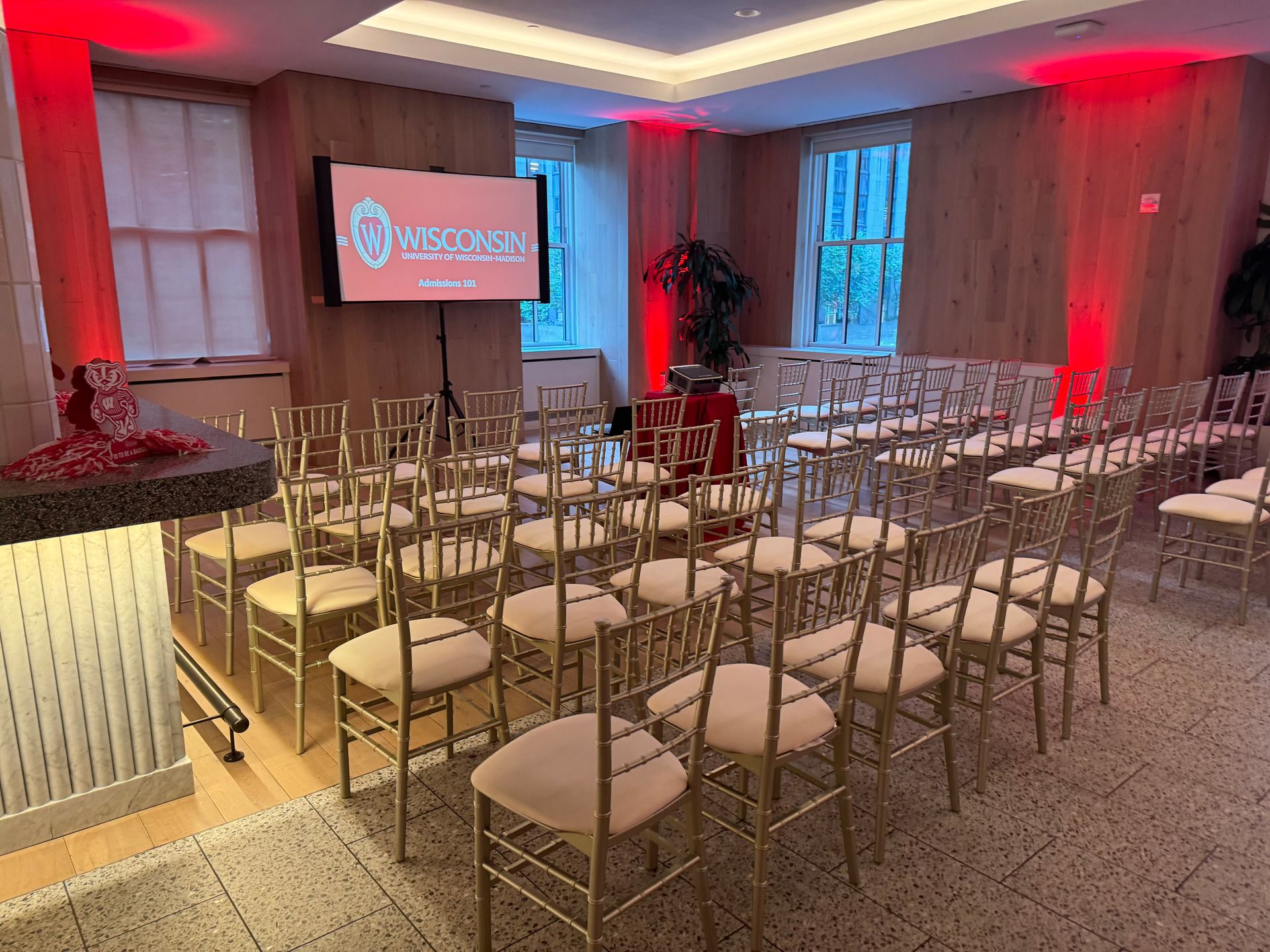 A room filled with rows of chairs and a large screen.