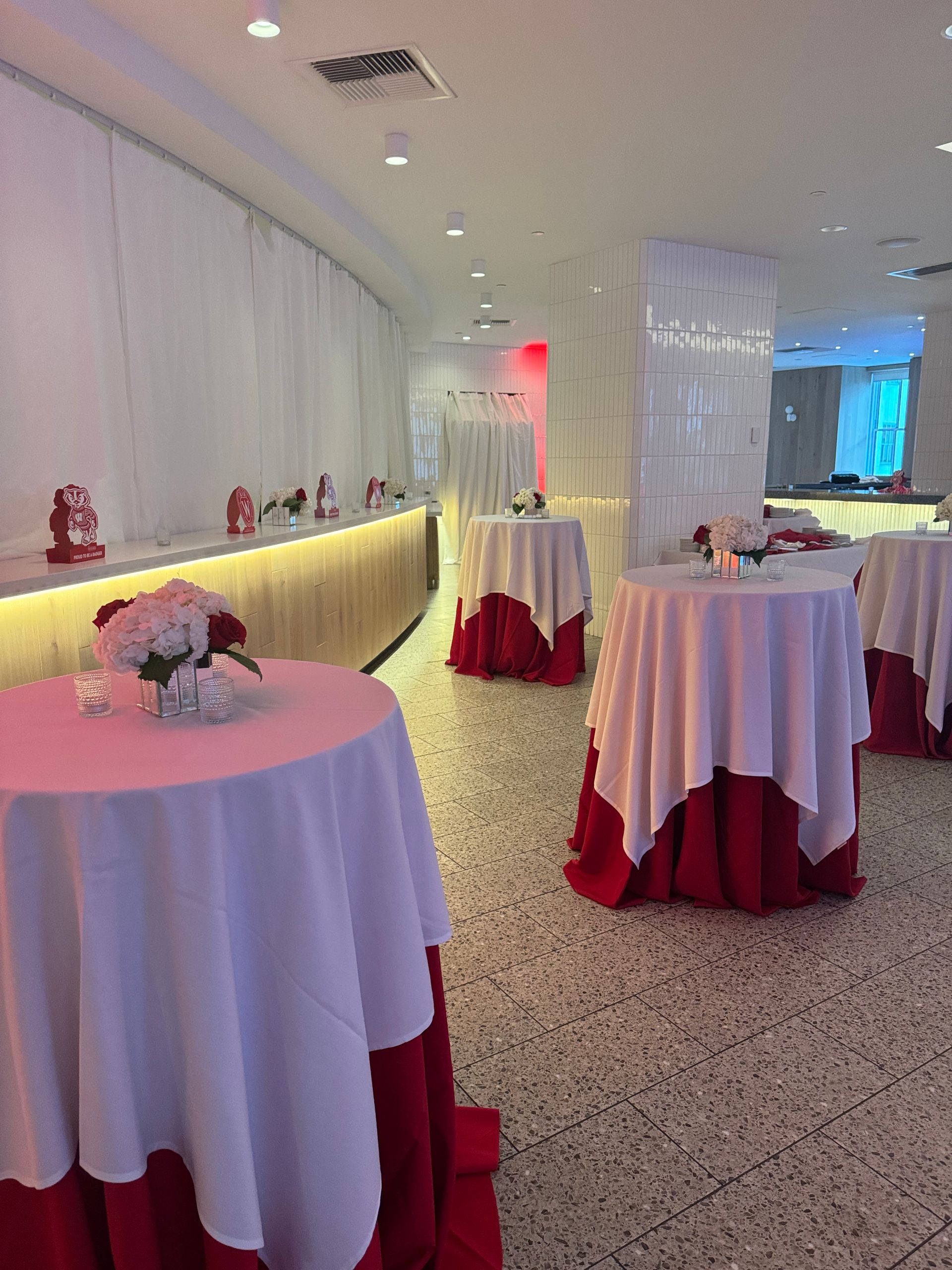 A row of tables with red and white tables cloths in a room.