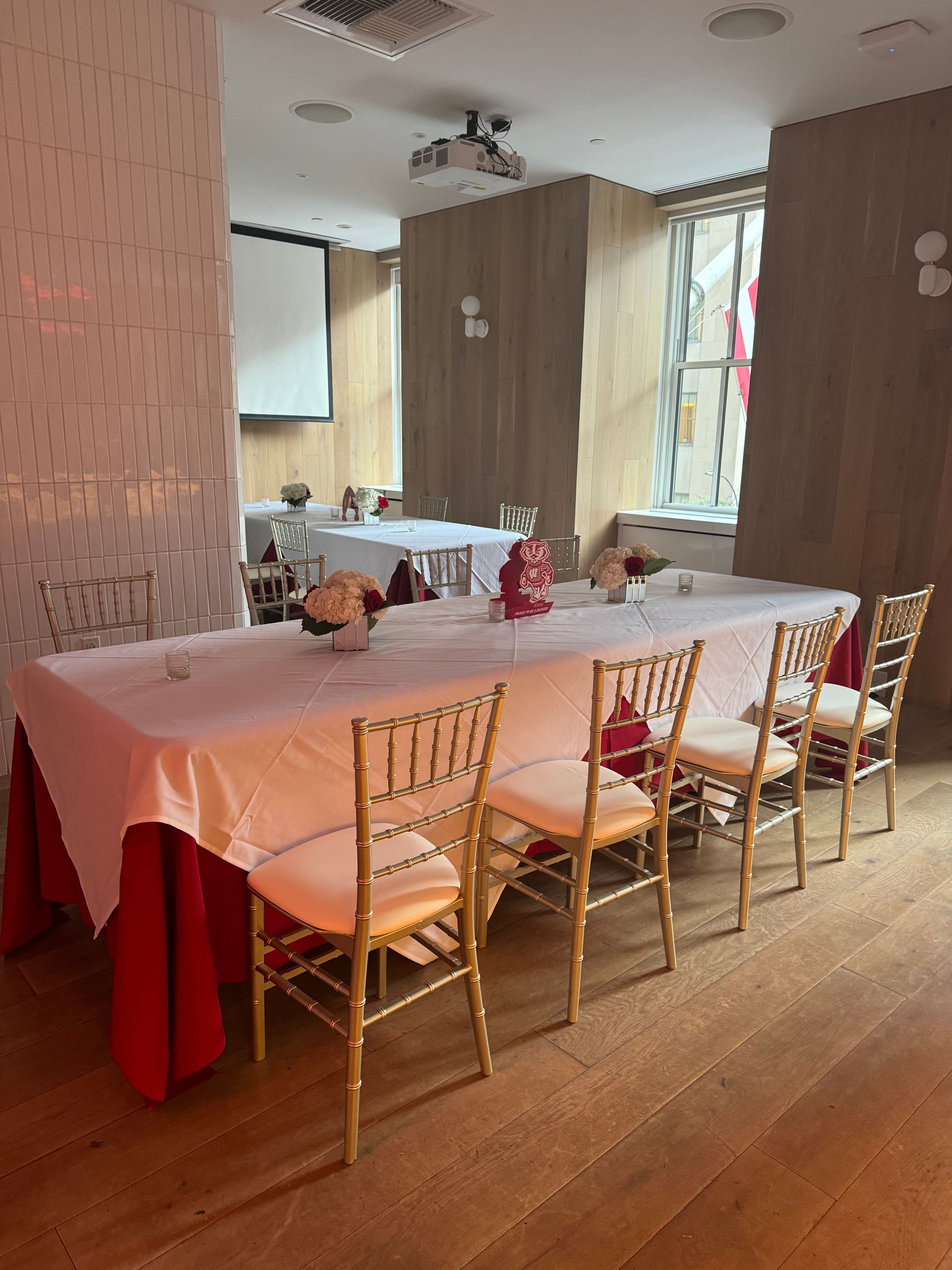A long table with a red tablecloth and gold chairs in a room.